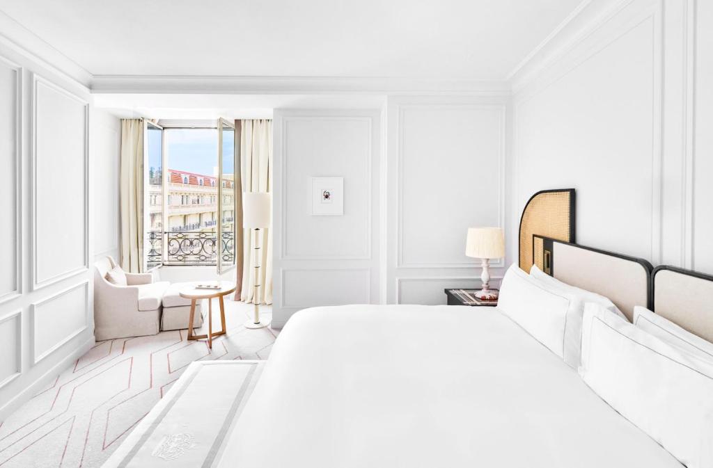 a white bedroom with a large bed and a window at Carlton Cannes, a Regent Hotel in Cannes