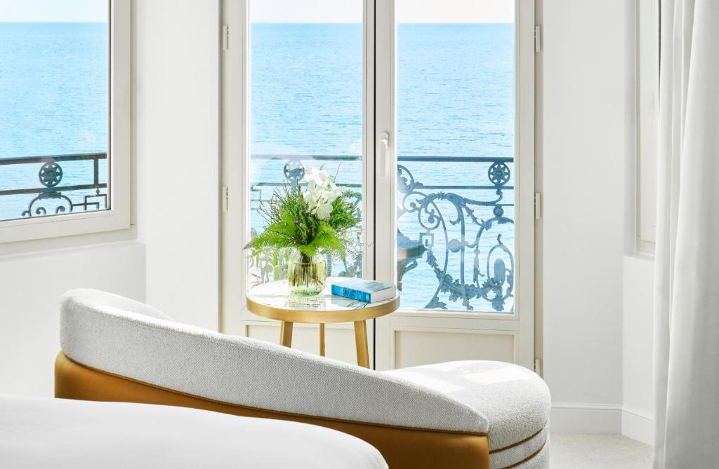 a room with a couch and a window with the ocean at Carlton Cannes, a Regent Hotel in Cannes