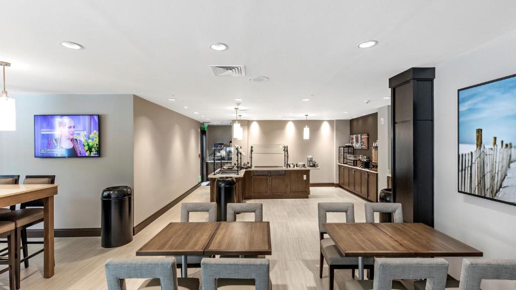 a restaurant with wooden tables and chairs and a kitchen at Staybridge Suites - Naples - Marco Island by IHG in Naples