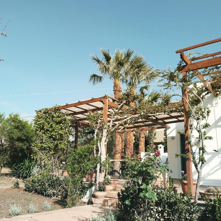 a house with a pergola and palm trees at Villa in the Garden in Kokkini Khanion