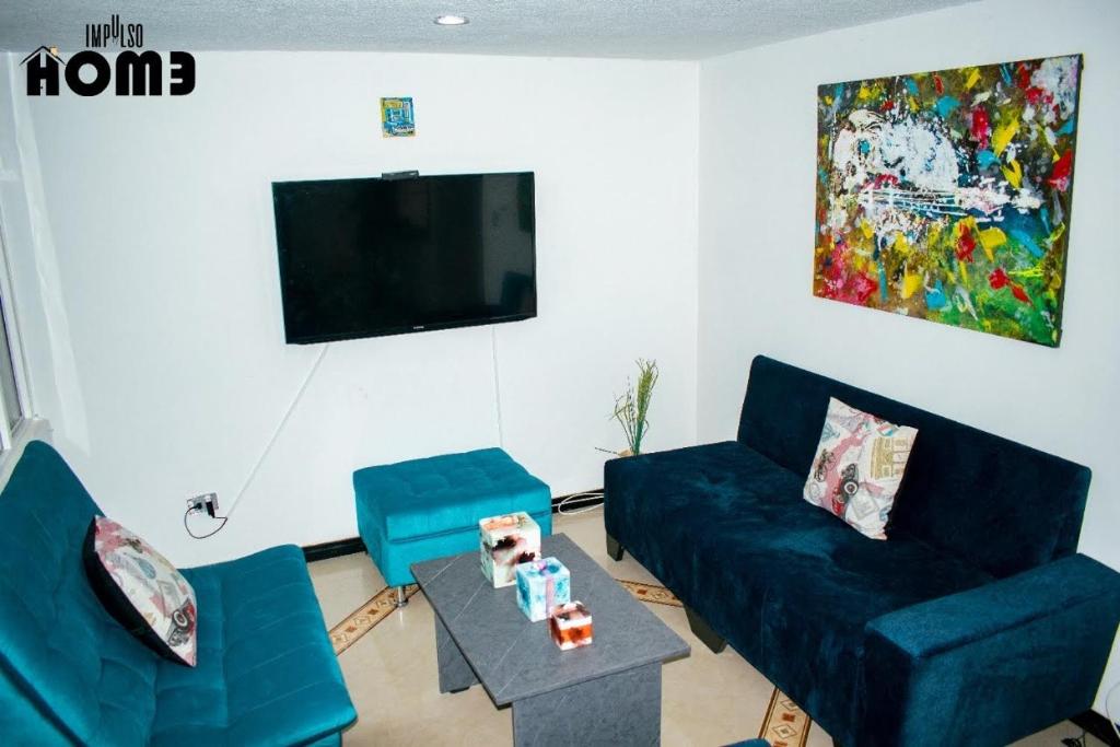 uma sala de estar com dois sofás azuis e uma mesa em Lilas Home em Pasto