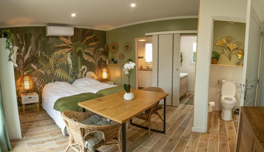 a bedroom with a bed and a table and a bathroom at Le colibri in Cazaubon