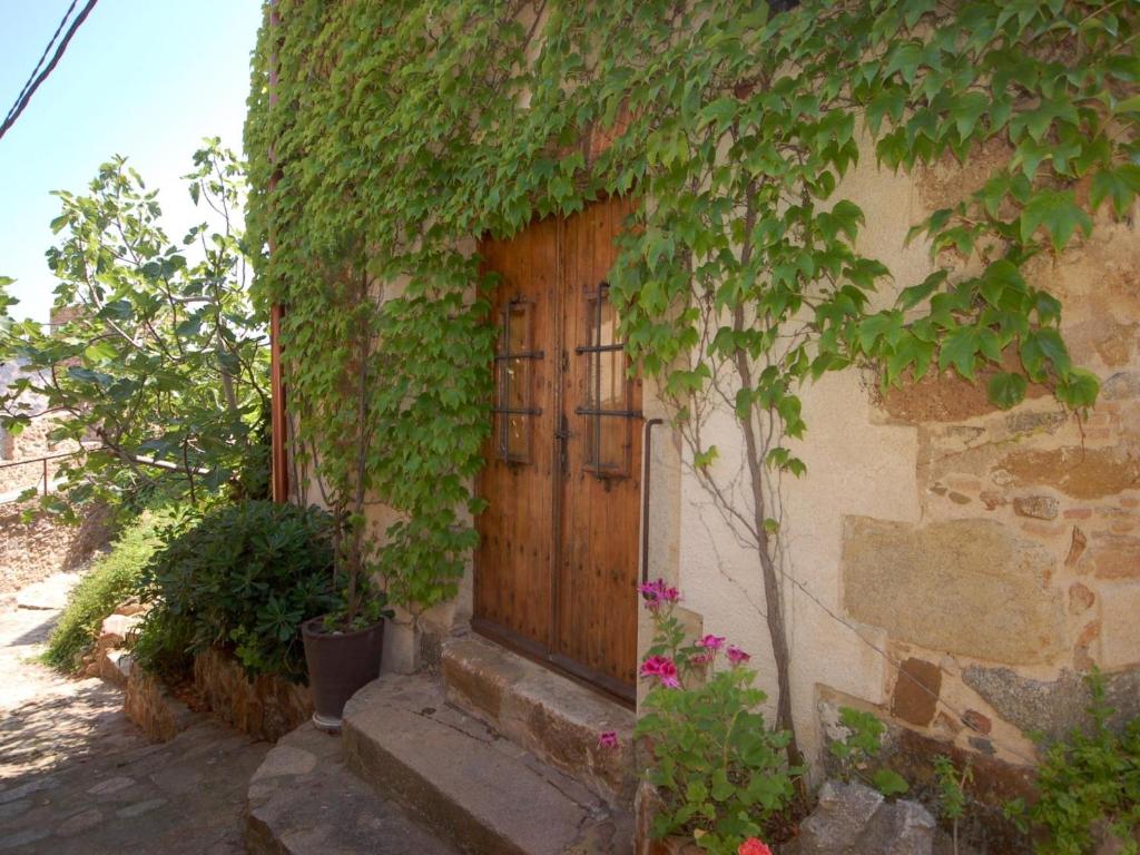a wooden door on a building with ivy at NICE HOUSE in VILA VELLA TOSSA DE MAR in Tossa de Mar
