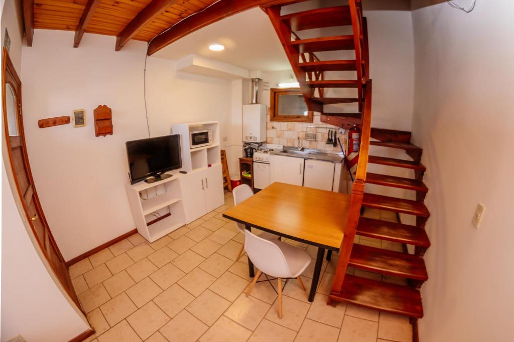 eine Küche mit einem Holztisch und einer Wendeltreppe in der Unterkunft Cabaña 1 Comoda, Cálida y Confortable in Ushuaia