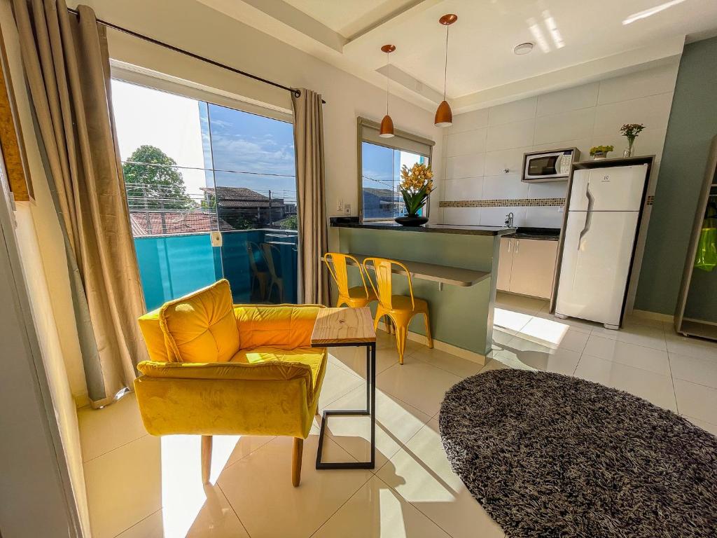 a living room with a yellow couch and a kitchen at Mangata Loft - Requinte e Conforto para Lazer ou Trabalho in Itanhaém