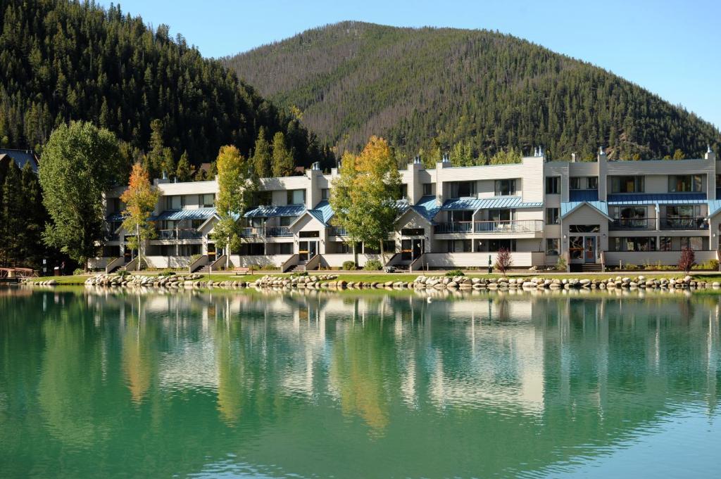 a large building next to a lake with a mountain at Lakeside Village by Keystone Resort in Keystone