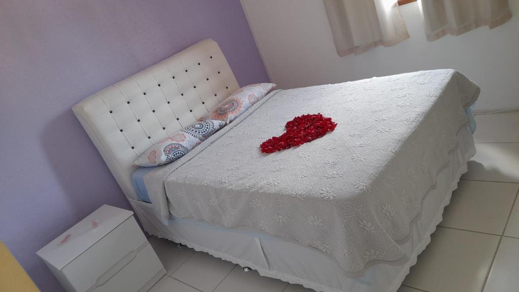 Una cama blanca con un corazón rojo. en Hospedaria Casa de Maria en Angra dos Reis