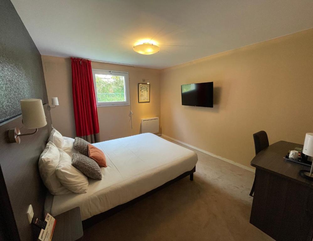 a small bedroom with a bed and a television at Hôtel Arcadia in Lannion