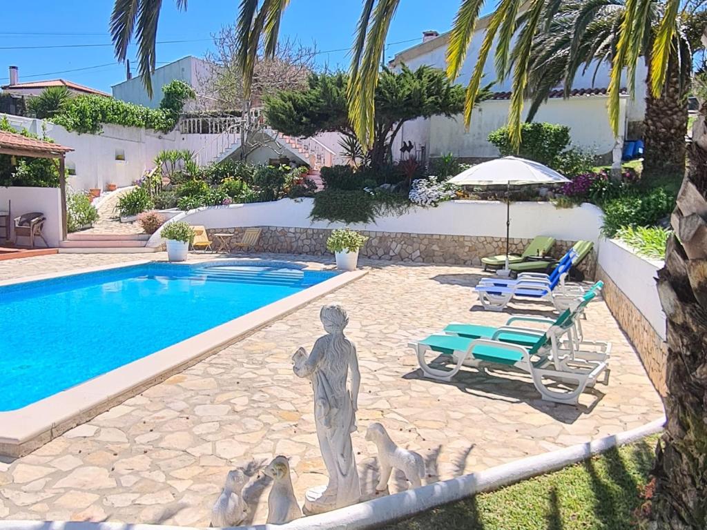 a statue of a man with three dogs by a swimming pool at Casa das Margaridas in Caldas da Rainha