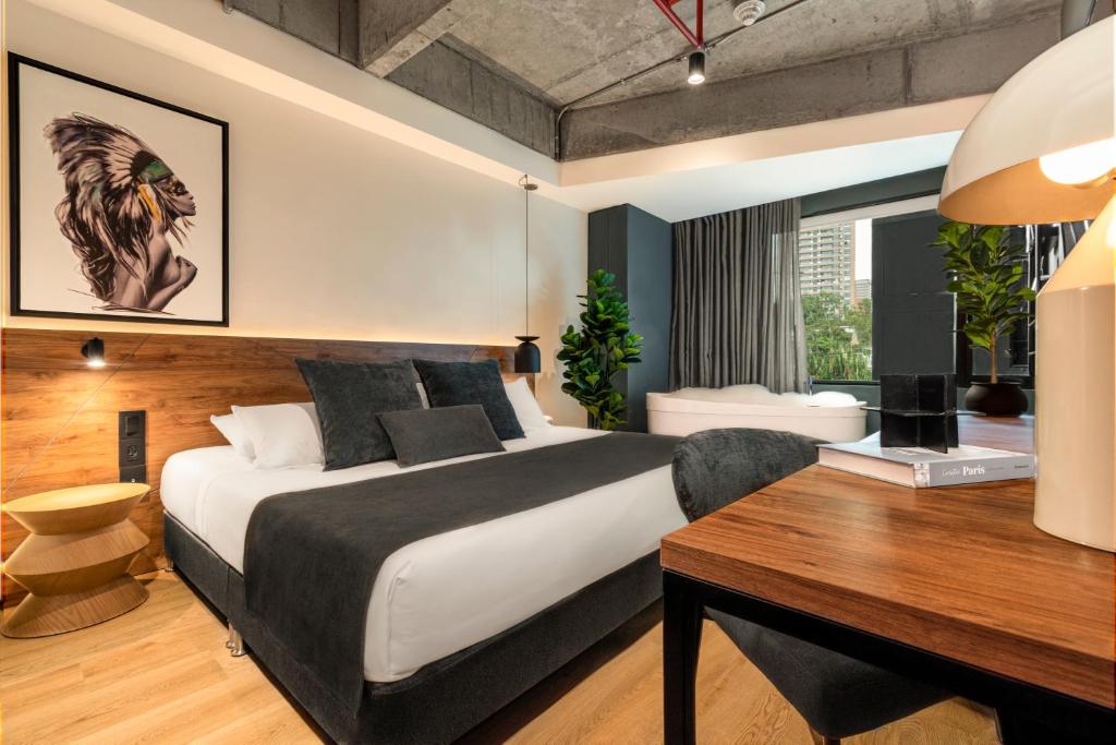 a bedroom with a large bed and a desk with a computer at HASHTAG 98 HOTEL in Medellín