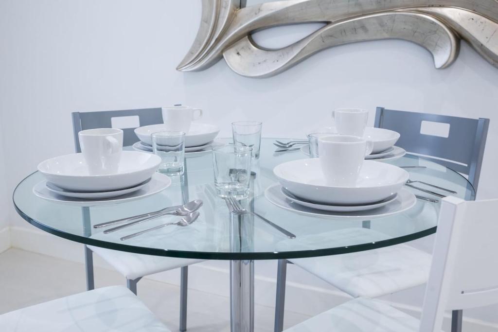 une table en verre avec des assiettes et des verres dans l'établissement Apartamento de Diseño en Plaza Mayor, à Madrid