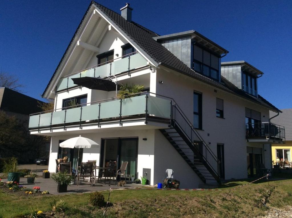 ein großes weißes Haus mit einem Balkon und einem Tisch in der Unterkunft Ferienwohnung Bodenseezauber in Langenargen