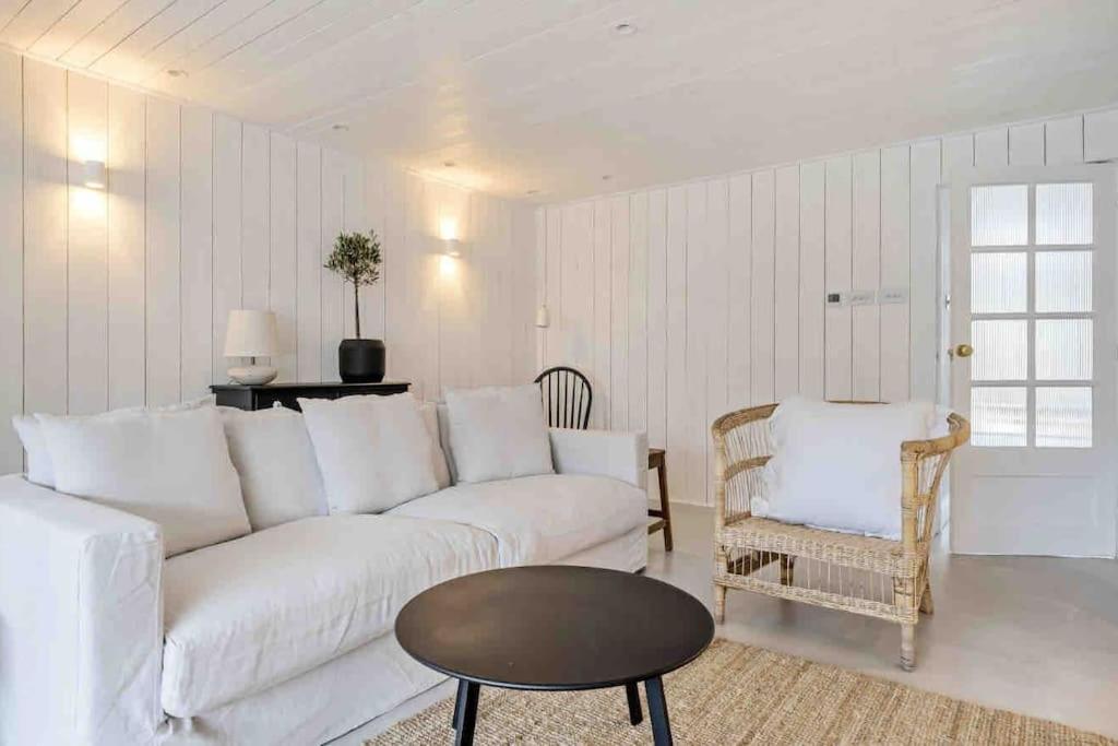 uma sala de estar com um sofá branco e uma mesa em sea side cottage *brand new* em West Wittering