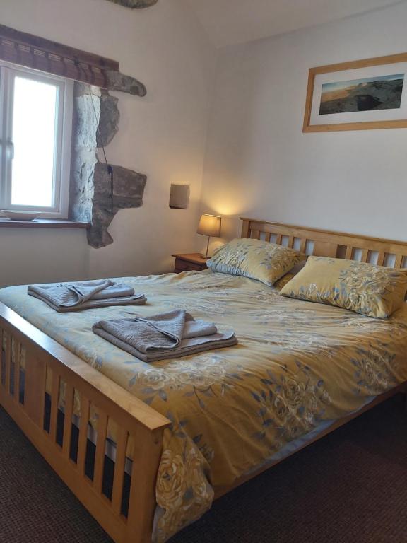 a bedroom with a large bed with towels on it at Family stay by the beach in Chwilog