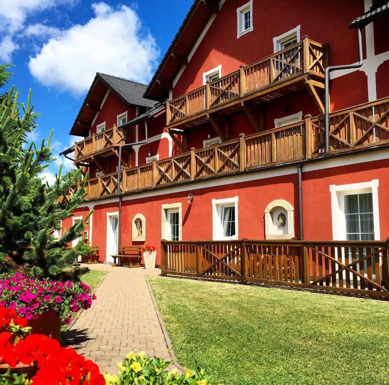 a red building with balconies and flowers in a yard at Hotel Barborka in Přední Výtoň