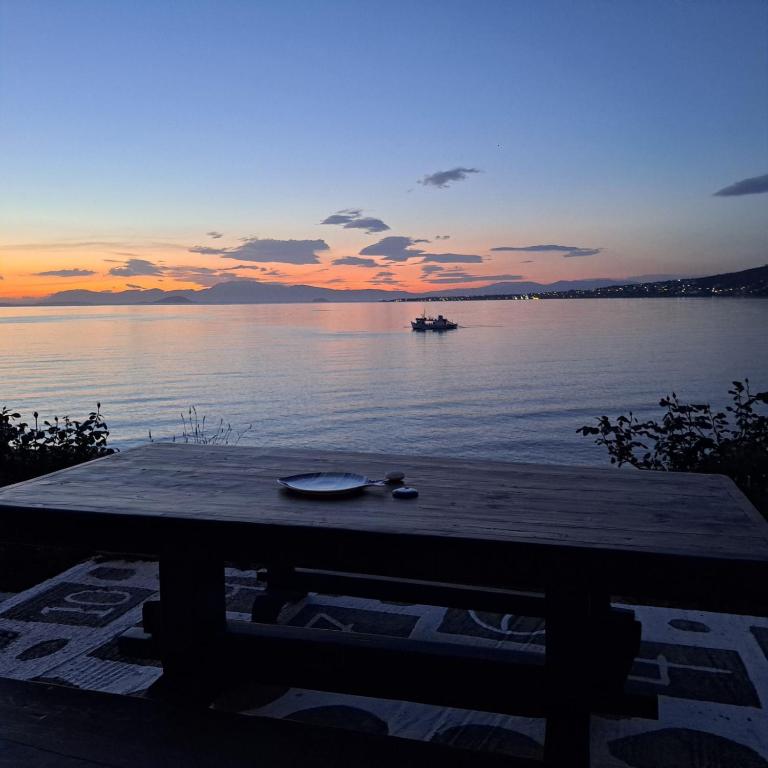 a boat in the water at sunset with a table at Almyra seaside in Perdika