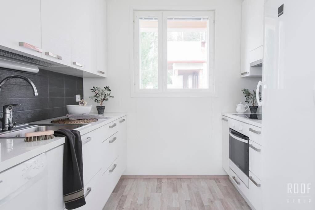 a white kitchen with white cabinets and a window at 100m2 moderni paritalo omalla pihalla Helsingissa in Helsinki