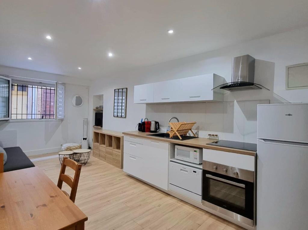 - une cuisine avec des appareils blancs et une table en bois dans l'établissement T2 Centre Historique Rénové, à Aix-en-Provence