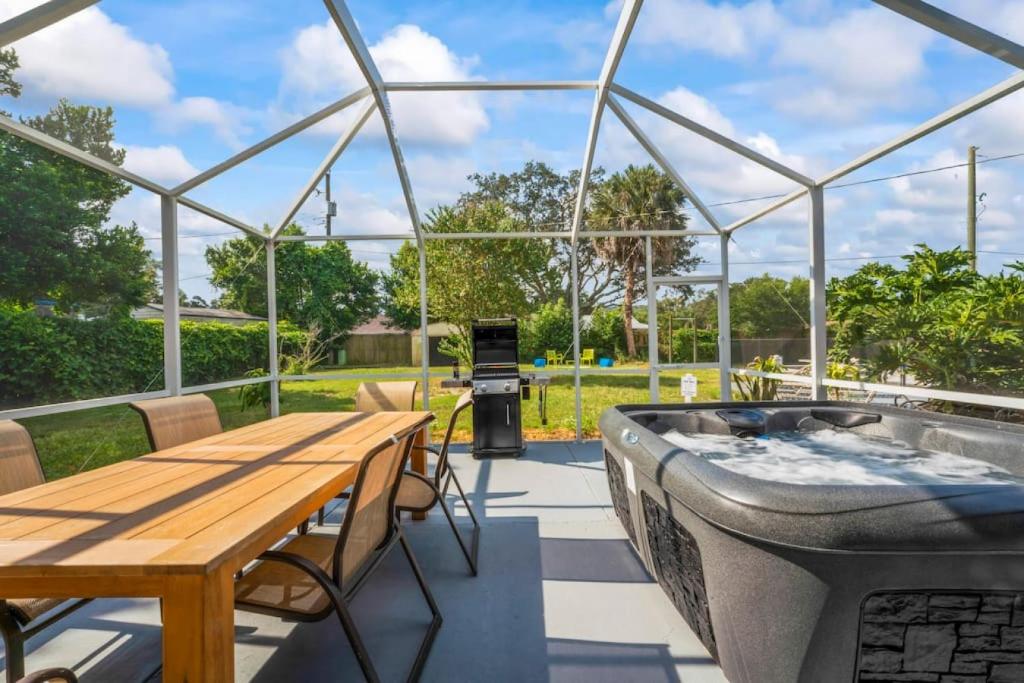 a patio with a hot tub and a wooden table and chairs at Oversized 4bed + Converted Bedroom, HEATED Pool + Hot Tub in Brandon