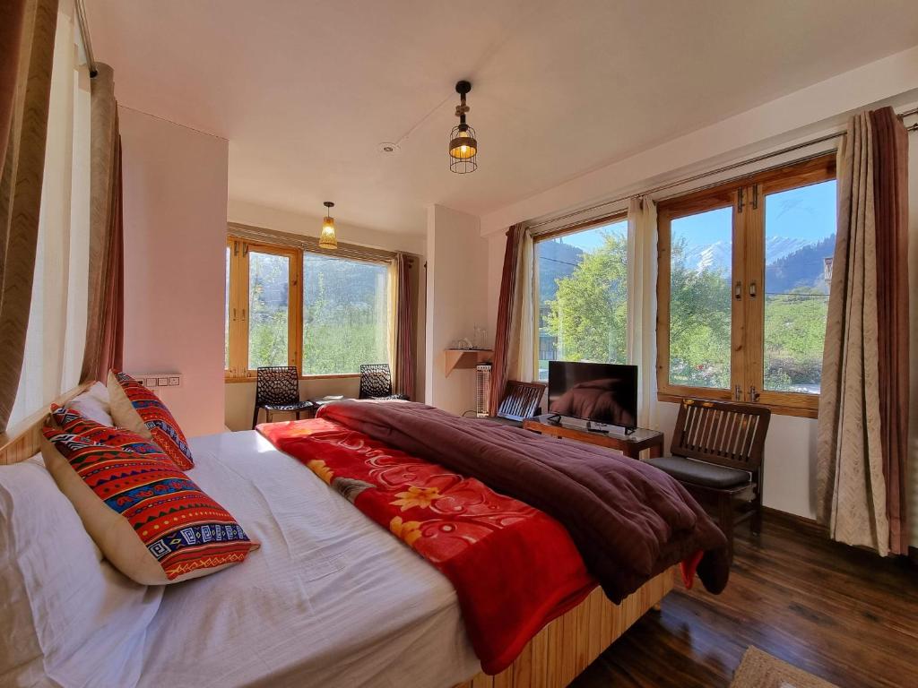 a bedroom with a large bed in a room with windows at The Bunker Burwa Manali in Manāli