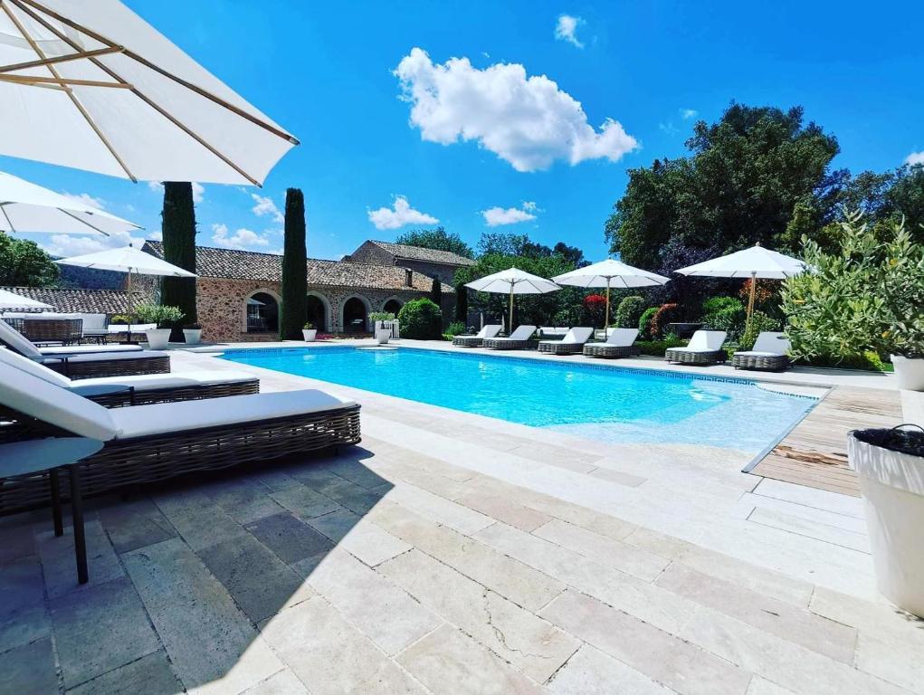 a swimming pool with lounge chairs and umbrellas at Domaine de la Citerne in Nans-les-Pins