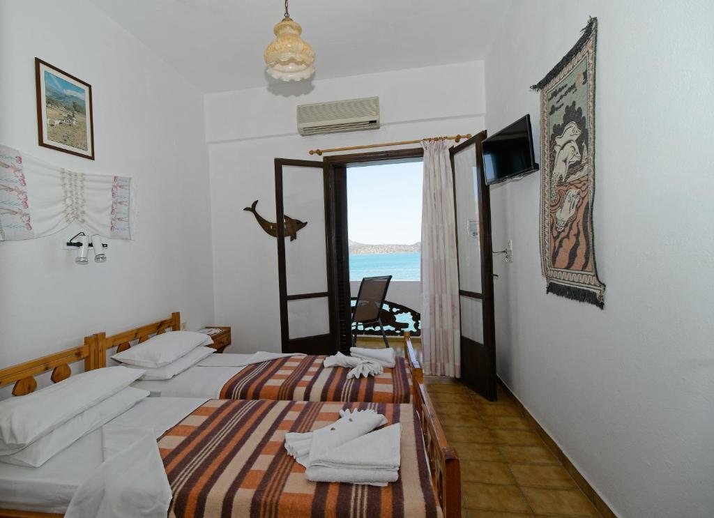 two beds in a room with a view of the ocean at Dolphins in Elounda