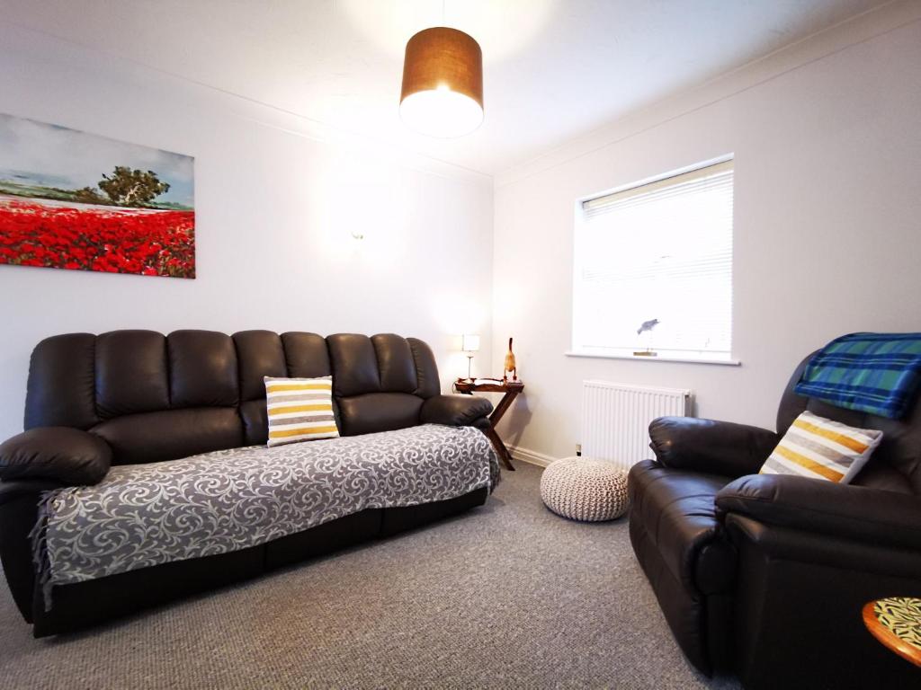 sala de estar con sofá de cuero y silla en Rose Cottage en Conwy