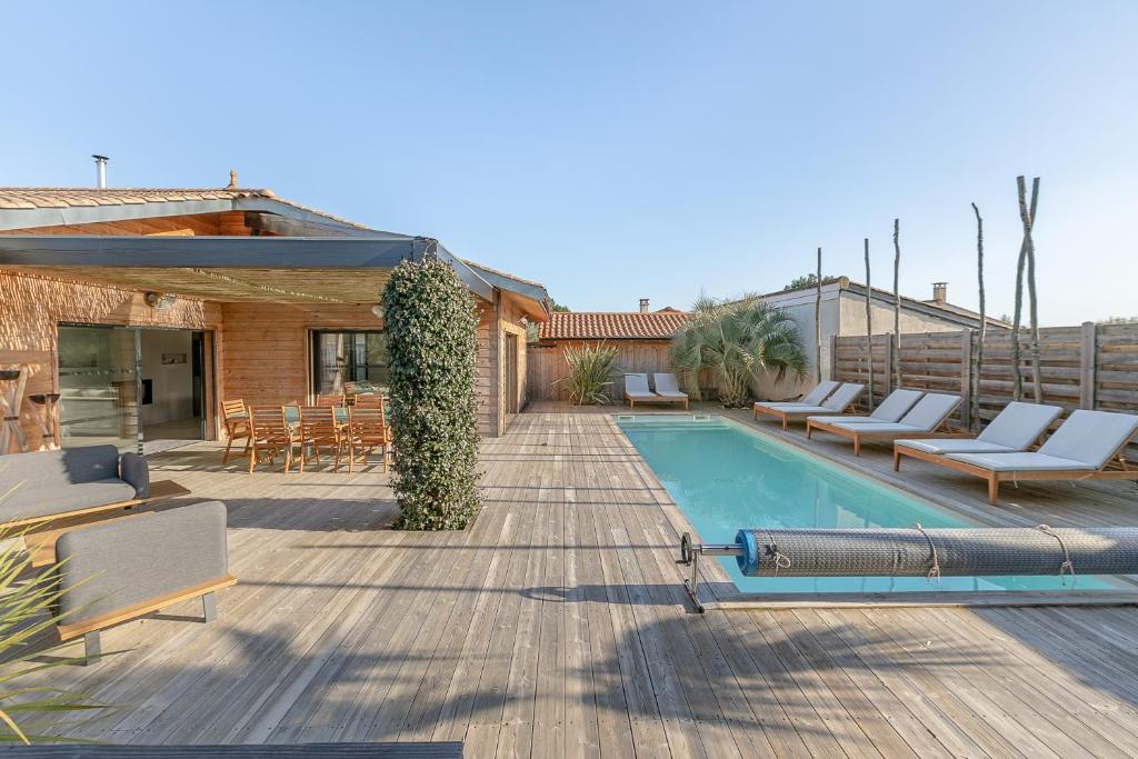 um quintal com piscina e cadeiras e uma casa em Villa privée 12 personnes piscine chauffée - ARES em Arès