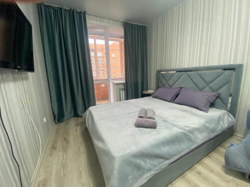 1 dormitorio con 1 cama con 2 toallas en Комфортабельные - уютные апартаменты в Костанай мкр Береке1, en Kostanái