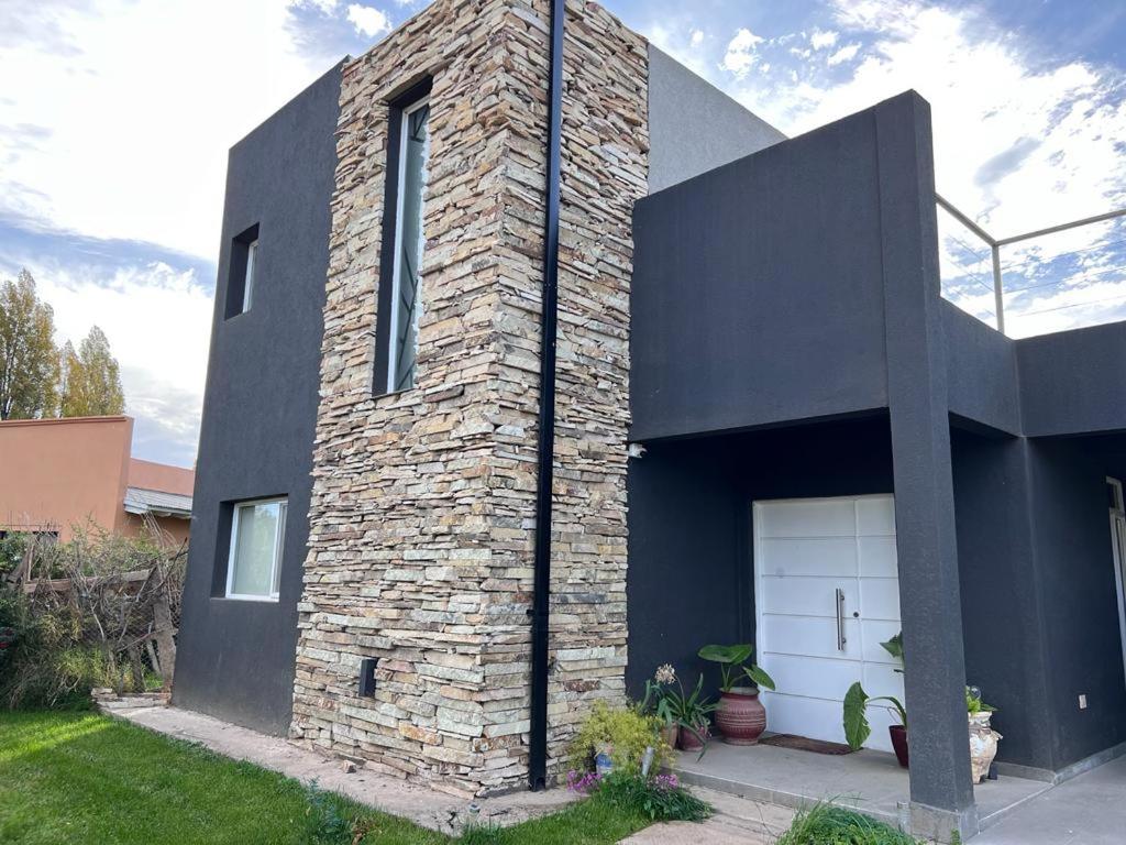 uma casa de tijolos com uma garagem branca em El mejor lugar Secreto em Plottier