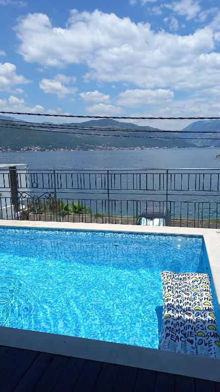 a large swimming pool next to a body of water at Ksenija apartman uz more in Krasici