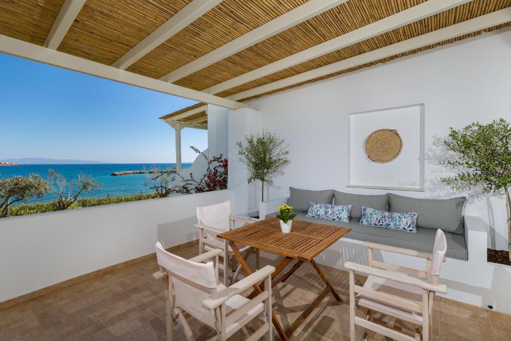 a dining room with a table and chairs and the ocean at La Mer Seaside Apartments in Drios