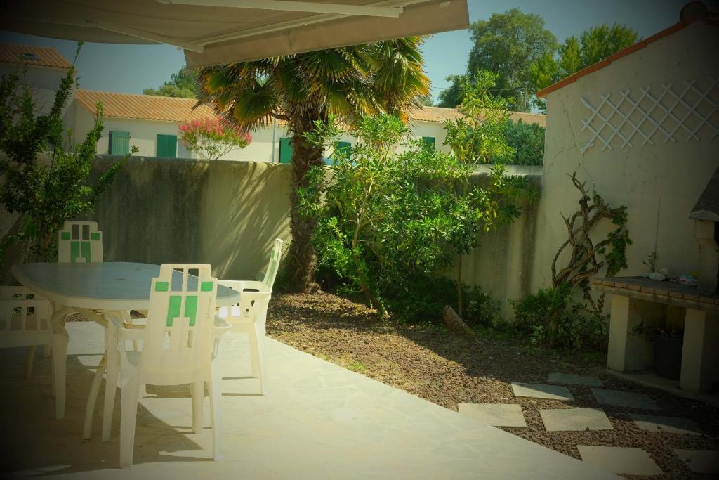 um pátio com uma mesa e cadeiras num quintal em La maisonnette des vacances em Saint-Georges-dʼOléron