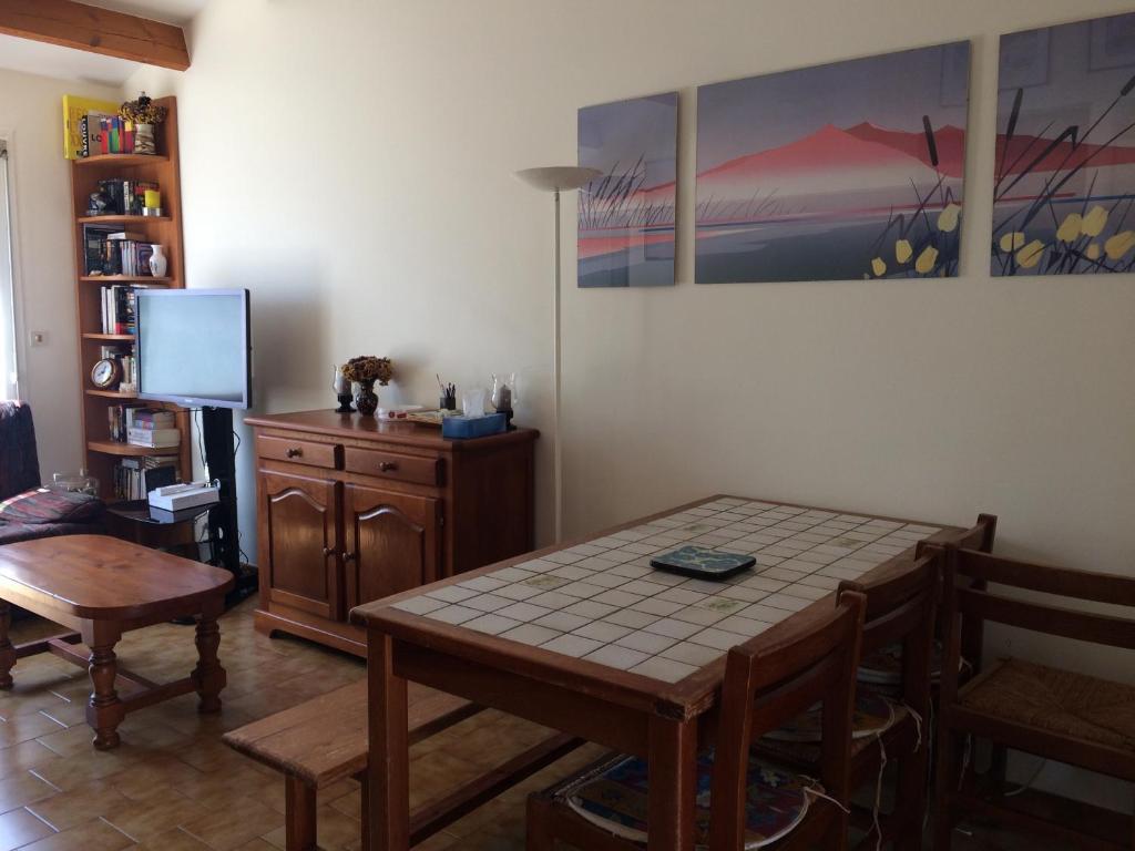 jadalnia ze stołem i krzesłami oraz telewizorem w obiekcie La maisonnette des vacances w mieście Saint-Georges-dʼOléron