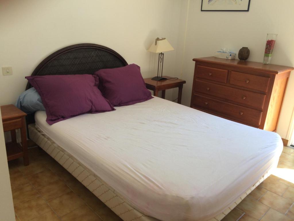 sypialnia z łóżkiem z fioletowymi poduszkami i komodą w obiekcie La maisonnette des vacances w mieście Saint-Georges-dʼOléron