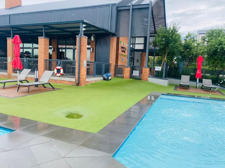 a swimming pool with chairs and a building at Greenpark Lifestyle Estate in Boksburg