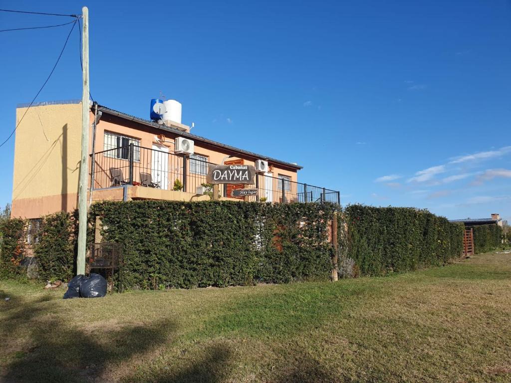 un edificio con un seto delante de una casa en Cabañas DAYMA en Trapiche