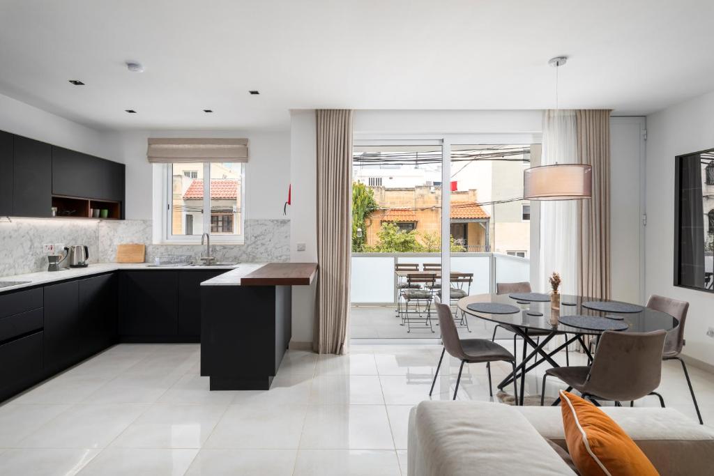 a kitchen and living room with a table and chairs at Modern 3BR Stylish Apartment with large Balcony - Close to St Julians and St Georges Bay in Is-Swieqi