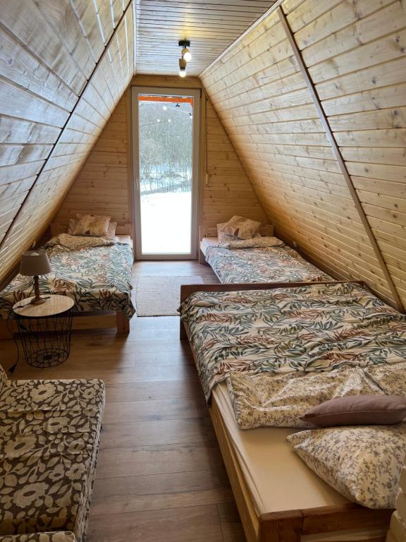 un dormitorio en el ático con 3 camas y una ventana en Domek nad Potokiem w Beskidach, en Rajcza