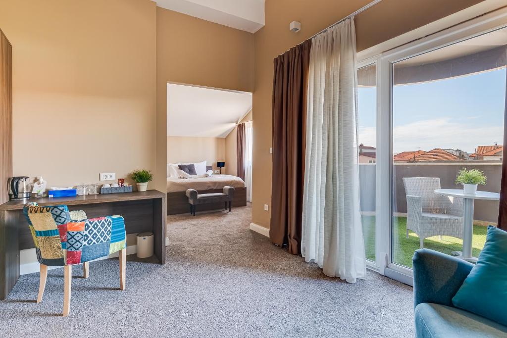 a living room with a desk and a bedroom at Hotel Sky in Zadar