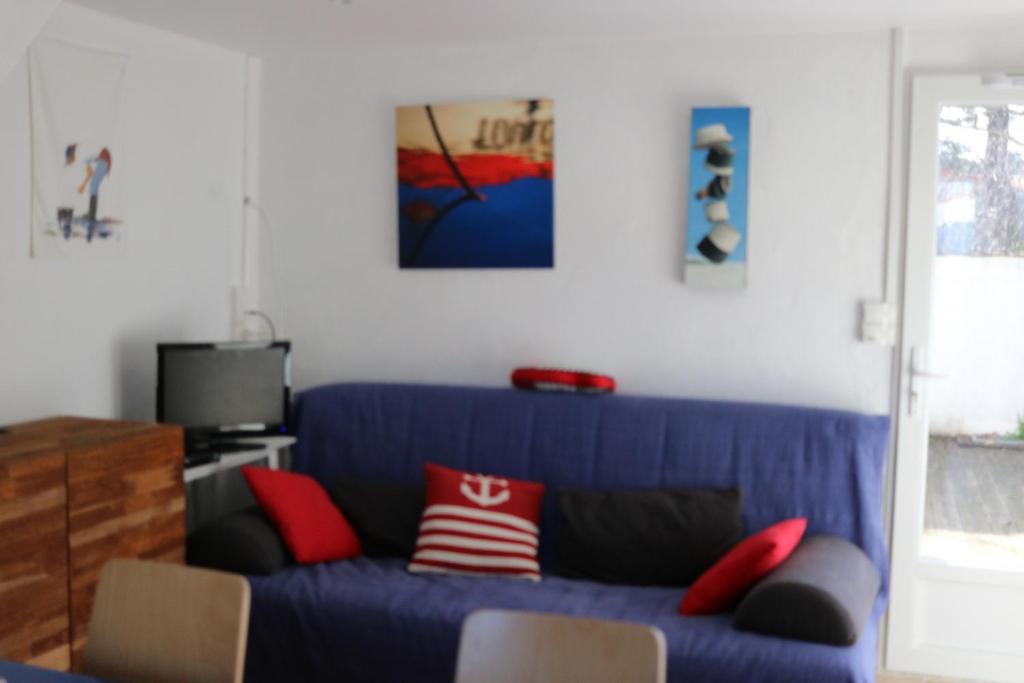 a blue couch with red pillows in a living room at La Villa K NARD au centre de Saint Trojan in Saint-Trojan-les-Bains
