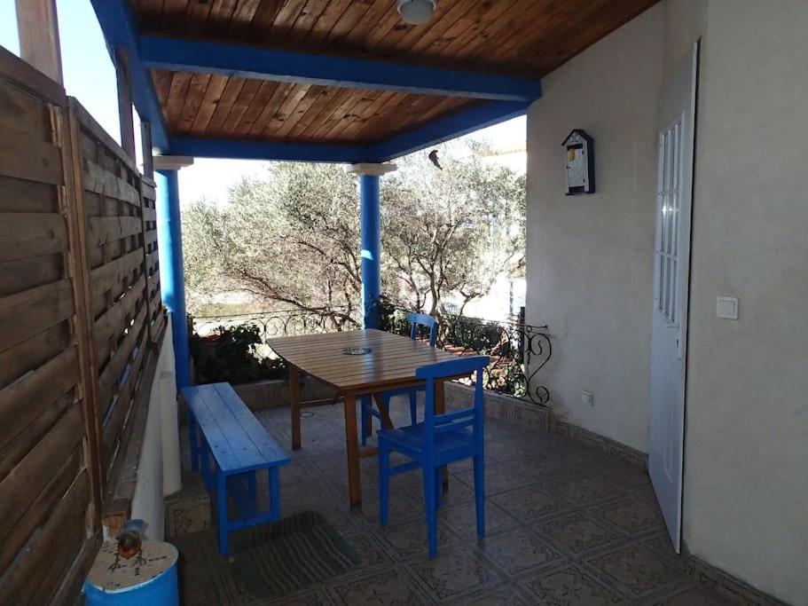 een veranda met een houten tafel en blauwe stoelen bij Petite maison bord et vue mer, 55 m2 in Martigues