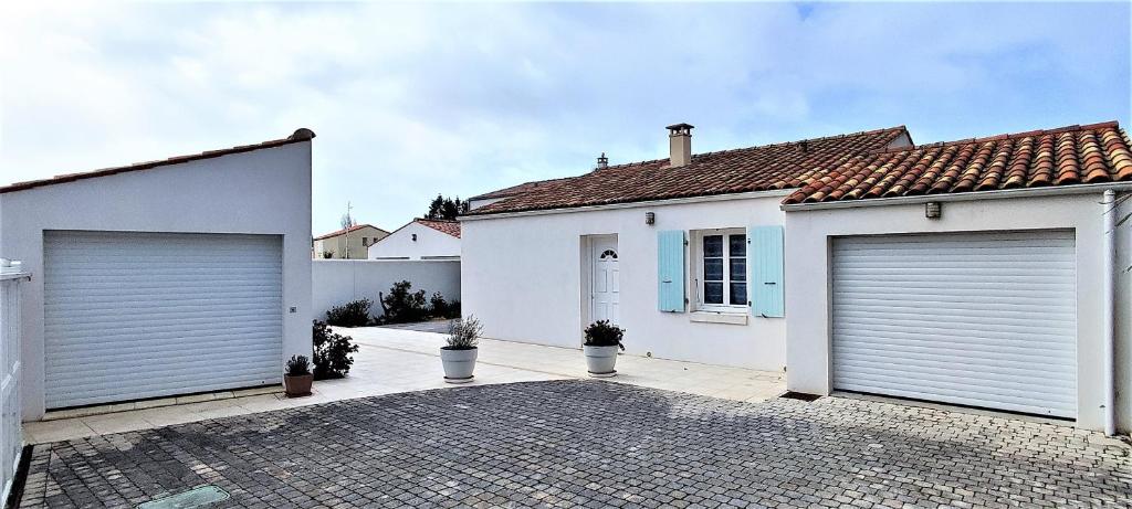 a white house with two garage doors on it at Villa Ohana proche centre-ville in Le Château-dʼOléron