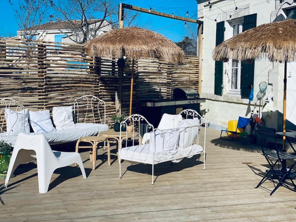 a patio with white chairs and a wooden deck at Villa Constantine a 2 pas du port de Boyardville in Saint-Georges-dʼOléron