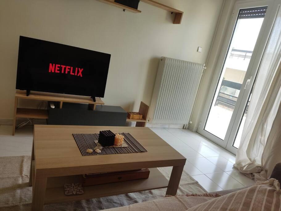 uma sala de estar com uma televisão e uma mesa de centro em M.V Apartment em Atenas