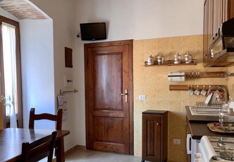 cocina con puerta de madera y mesa en Ànita holiday house, en Montemerano