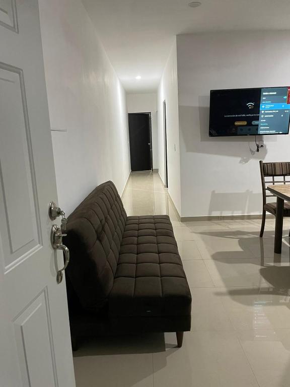 a living room with a couch and a tv on a wall at Departamento 103 in Mazatlán