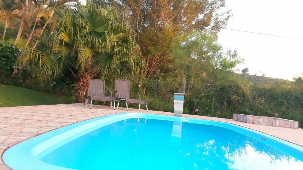 - une piscine bleue avec 2 chaises à côté dans l'établissement Chácara meu doce, à Socorro
