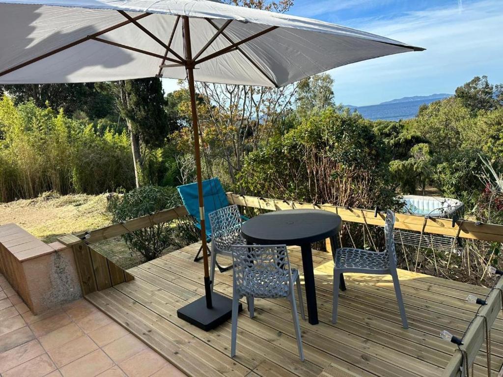 una mesa y dos sillas y una sombrilla en una terraza en Le jardin de Neptune en Rayol-Canadel-sur-Mer