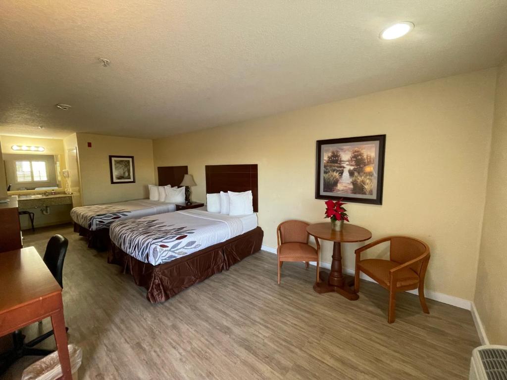 ein Hotelzimmer mit 2 Betten, einem Tisch und Stühlen in der Unterkunft Kenedy Inn and Suites in Kenedy